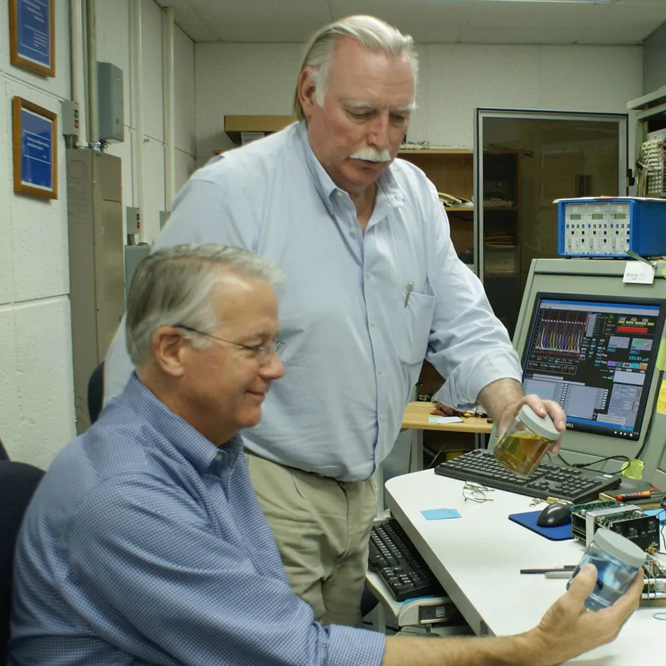 Tim Roehl and George Braly inside GAMI's test cell holding fuel containers.